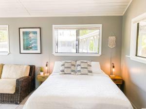 a bedroom with a bed and a chair and two windows at Surf Getaway, Queen Bed, Private Lanai in Keaau