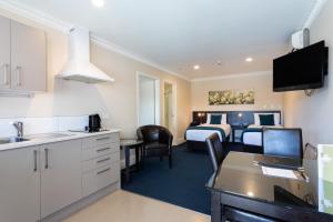 a hotel room with a kitchen and a bedroom at Tuakau Hotel in Tuakau