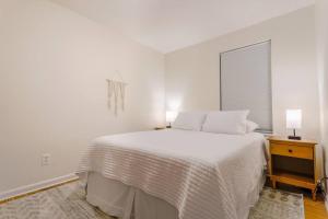 a white bedroom with a bed and a window at Saratoga Serenity: Charming Rental Nearby Downtown in Saratoga Springs