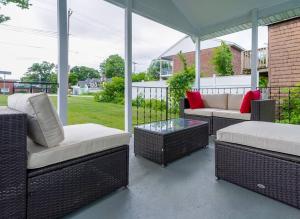 een veranda met rieten stoelen en tafels op een patio bij Saratoga Serenity: Charming Rental Nearby Downtown in Saratoga Springs