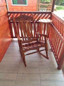 une chaise à bascule en bois assise sur une terrasse couverte dans l'établissement Cabinas Tortuguero Sports Fishing, à Tortuguero