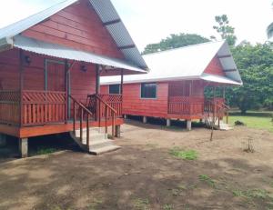 ein rotes Haus mit einer Veranda und einem weißen Dach in der Unterkunft Cabinas Tortuguero Sports Fishing in Tortuguero