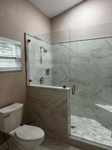 a bathroom with a toilet and a glass shower at Tampa Bay Oasis in Tarpon Springs