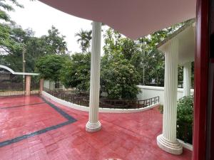 a porch with white columns and a red tile floor at Dream house in Atgaon
