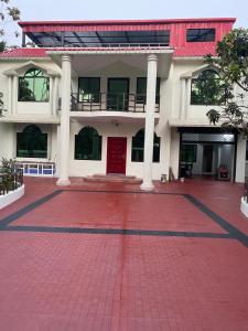 a large white building with a red brick courtyard at Dream house in Atgaon