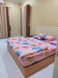 een groot bed met roze en blauwe bloemen erop bij Alfanama D’Homestay in Sungai Petani