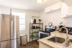 a kitchen with a stainless steel refrigerator and a sink at Lovely historic apt near Amelia Arena + Hyde Park in Tampa