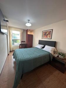 sypialnia z łóżkiem z zieloną kołdrą w obiekcie Hotel Palmas Reales w mieście Trujillo