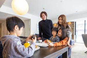 una familia sentada en una mesa comiendo comida en The Vale Niseko, en Niseko