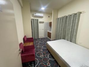 ein kleines Zimmer mit einem Bett und zwei roten Stühlen in der Unterkunft Budgeted vacation Homes Rental LLC in Dubai