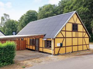 ein gelbes Haus mit schwarzem Dach in der Unterkunft Holiday home Rødby III in Rødby