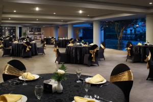 a banquet hall with black tables and chairs with yellow napkins at eL Hotel Malang in Malang