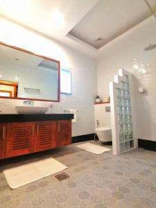 a bathroom with a sink and a mirror and a toilet at Vida Homes Condo Resort in Dauin