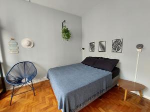 um quarto com uma cama com um cobertor azul e uma cadeira em Studio pertinho do mar! Pitangueiras/Guarujá no Guarujá