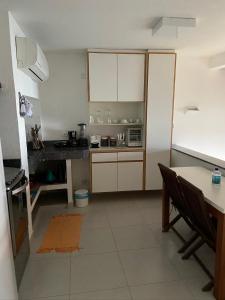 una cocina con armarios blancos, una mesa y una barra en Casas Do Mar en Ilhabela