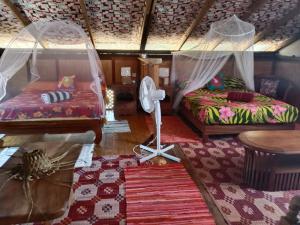 Sala de estar con 2 camas y mesa en Chalet chez Téra'i en Avatoru