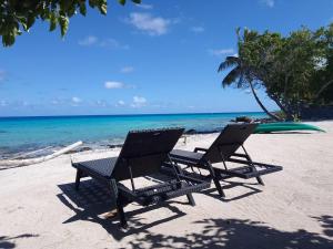 - deux chaises et une table sur une plage dans l'établissement Chalet chez Téra'i, à Avatoru