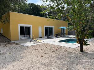 un bâtiment jaune avec une piscine et une maison dans l'établissement Brand new villa with fully intergrated Air conditioning & private pool, Overlooking forest, à Sardan