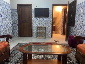 ein Wohnzimmer mit einem Couchtisch und einem TV in der Unterkunft Maison-villa familiale in Azemmour