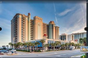 a large building with palm trees in front of a street at Flip Flop at Compass Cove in Myrtle Beach