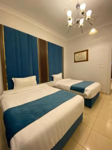 duas camas num quarto de hotel com cortinas azuis em منتجع أرين للوحدات السكنية em Al Hada