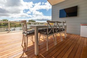 een terras met een tafel en stoelen en een televisie bij Pina Colada Shack-40 Marina Way in Mannum