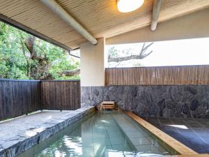 白浜町にあるTabist 南紀白浜 旅館万亭の木製の柵のある裏庭のスイミングプール