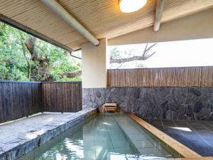 a swimming pool in a backyard with a wooden fence at Tabist Nanki Shirahama Ryokan Mantei in Shirahama