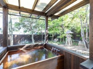 un étang de carpes koï intérieur dans une maison en bois avec une grande fenêtre dans l'établissement Tabist Nanki Shirahama Ryokan Mantei, à Shirahama
