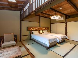 Tabist Nanki Shirahama Ryokan Mantei في شيراهاما: غرفة نوم بسرير كبير وكرسي