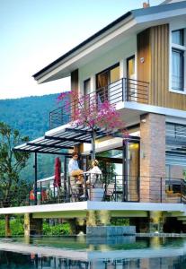 een huis met mensen op een balkon naast het water bij Nam Casa Sân Golf Tam Đảo Venuestay in Tam Ðảo
