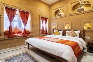 a bedroom with a large bed and two windows at Hotel Heritage Haveli in Jaisalmer