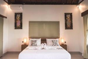 een slaapkamer met een wit bed met twee zwanen erop bij Villa Puri Kembar in Ubud