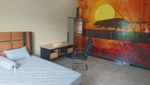 sypialnia z łóżkiem, biurkiem i obrazem w obiekcie Unterkunft in der Nähe des Flughafens Kuala Namu Medan w mieście Kampungbesar