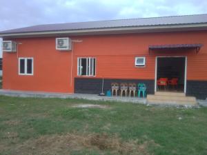 een rood huis met stoelen ervoor bij Unterkunft in der Nähe des Flughafens Kuala Namu Medan in Kampungbesar