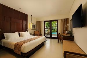 a hotel room with a large bed and a television at Padma Resort Legian in Legian