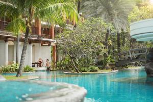 a swimming pool in a resort with palm trees at Padma Resort Legian in Legian