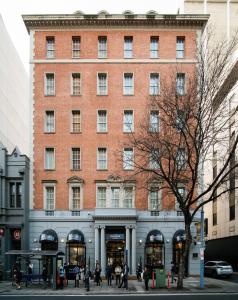 a large brick building with people walking in front of it at The Chancellor on Currie in Adelaide