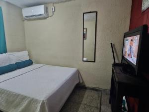 een kleine kamer met een bed en een televisie bij Cat House in Nueva San Salvador