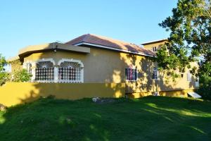 una casa gialla con un cortile verde davanti di Cozy Locale - Gold a Port Antonio