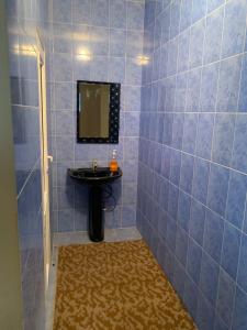 W wyłożonej niebieskimi kafelkami łazience znajduje się umywalka i lustro. w obiekcie Guest House w mieście Czołponata