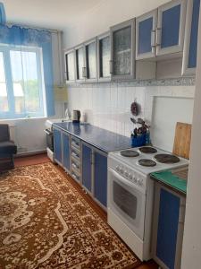 a kitchen with a white stove and blue cabinets at Guest House in Cholpon-Ata