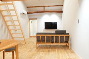 a living room with a couch and a tv and a staircase at Rikka Fukiya in Takayama