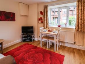 a living room with a table and a red rug at Cupid's Cottage in Bessingby