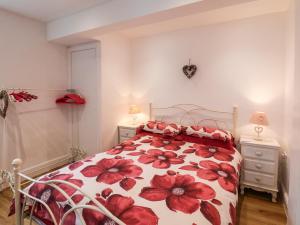 a bedroom with a bed with a red floral bedspread at Cupid's Cottage in Bessingby