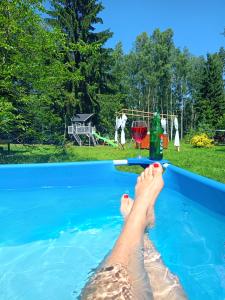a person laying in a swimming pool with a glass of wine at Jurty w Lesie KotfaLas in Skarżysko-Kamienna
