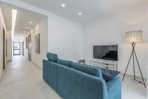 un soggiorno con divano blu e TV di St Julians Apartment a San Giuliano