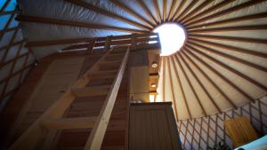a spiral staircase in a yurt with a round window at Jurty i namioty w Lesie KotfaLas Glamping Świętokrzyskie-SPA in Skarżysko-Kamienna
