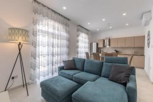 a living room with a blue couch and a kitchen at St Julians Apartment in St. Julianʼs