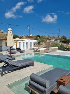 een zwembad met 2 ligstoelen en een parasol bij Abelos Mykonos in Mykonos-stad